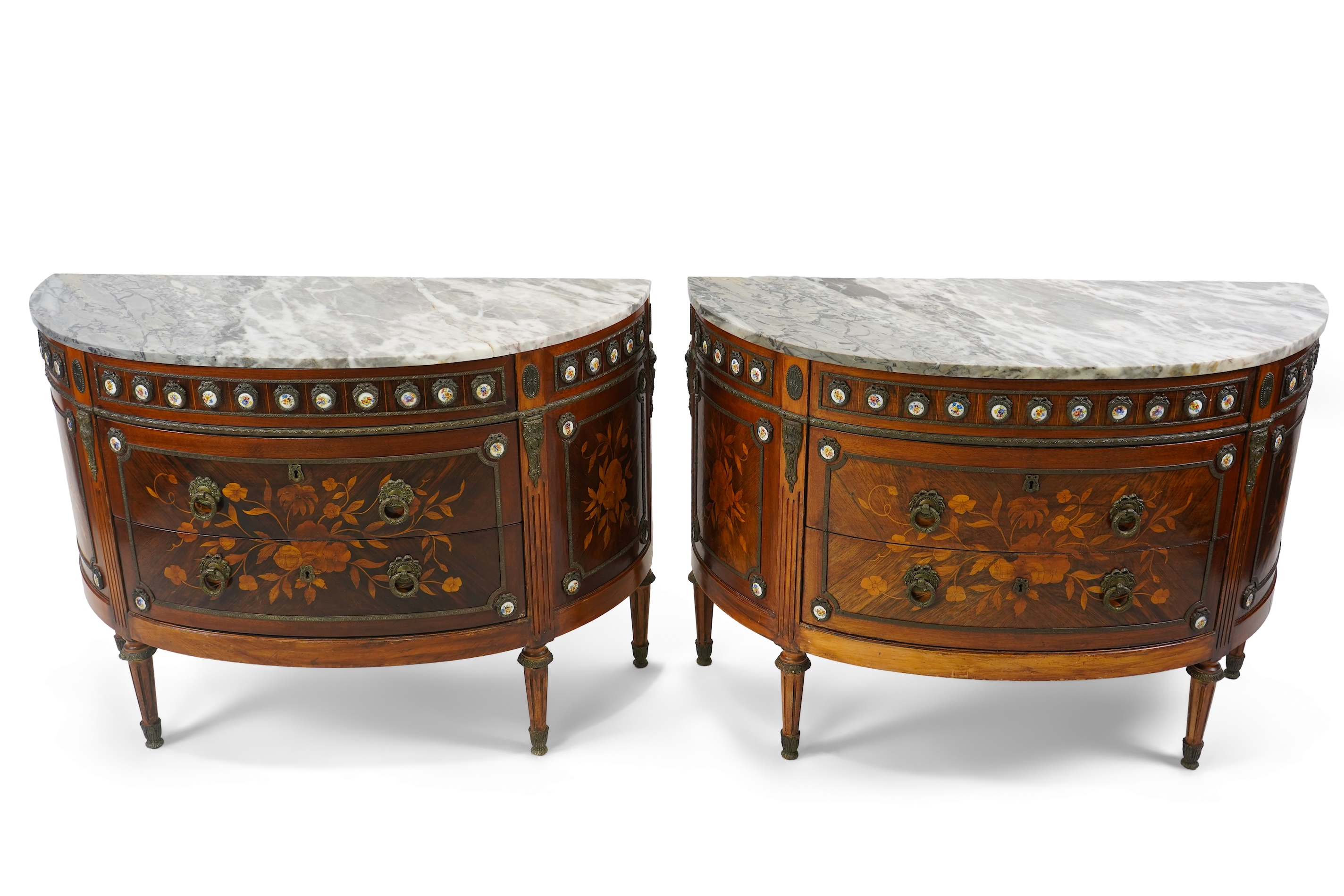 A pair of early 20th century French marquetry inlaid, gilt metal and porcelain mounted rosewood and beech demi-lune commodes